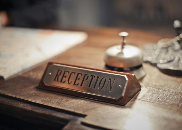 Close-up of a hotel reception desk showcasing a service bell and signage, emphasizing hospitality.